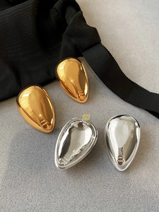 Macro detail of tear drop metal earrings in gold and silver with a mirror polish finish
