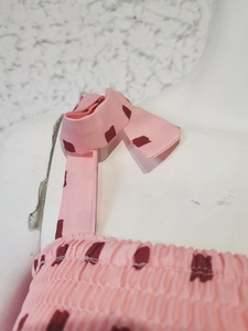 Close-up of pink geometric print dress detailing the shoulder straps and ruffled neckline