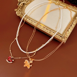 Detail of elegant gold layered necklaces with red rocking horse and white pearl beads