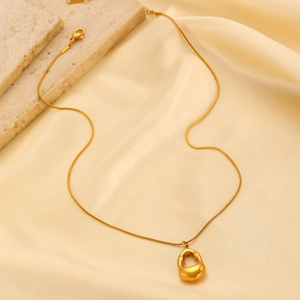 Detail of gold teardrop pendant necklace on beige silk with natural stone texture