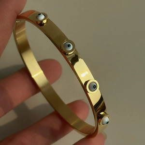 18k gold plated stainless steel bangle with evil eye charms and polished finish