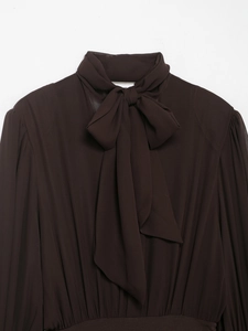Detail of high neck bow tie and pleated shoulder seams on dark brown long sleeve dress