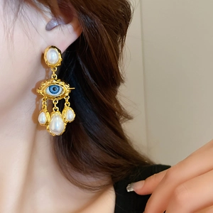 Detail of vintage gold evil eye earrings with pearls on a model side profile view
