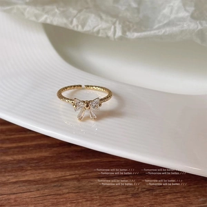 Close-up of gold bow ring with micro-pave zircons and an adjustable textured band