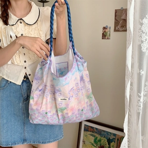 Detailed shot of floral tote bag featuring blue woven rope straps and large capacity