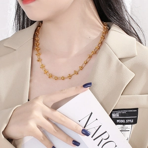Modieuze gouden roestvrijstalen knoopketting gedragen door model in minimalistische look