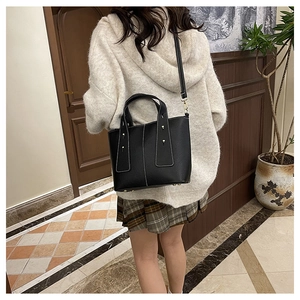 Détail d'un cabas en cuir noir avec surpiqûres blanches et rivets dorés de luxe