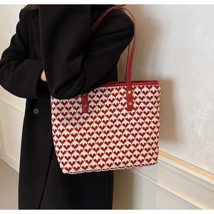 Close-up of red and white heart textured tote bag featuring premium leather straps