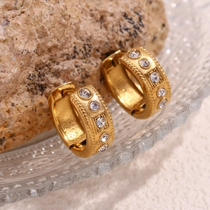 Macro shot of 18K gold plated twisted earrings with pavé rhinestones on frosted glass