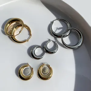 Detail von goldenen und silbernen Chunky-Creolen in verschiedenen Größen auf Keramiktablett