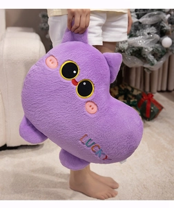 Close-up of a soft purple plush cat toy with LUCKY embroidery in a cozy festive setting