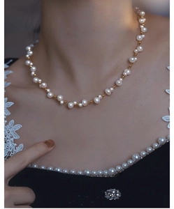 Detail of elegant double-layer pearl necklace with gold beads on black lace clothing