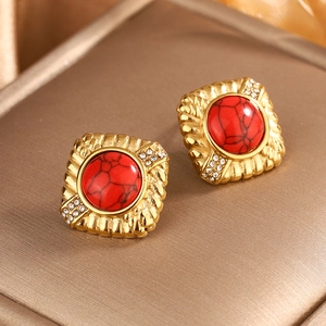 Detail of vintage square gold stud earrings with a red stone center and zircon accents