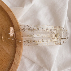 Close-up of a large rectangular hair clip with gold glitter in transparent resin