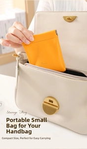 Close-up of orange leather squeeze pouch being placed inside a white tote bag for storage
