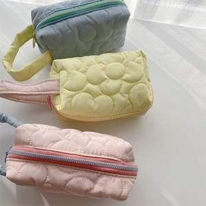 Close-up of quilted floral nylon cosmetic bags in macaron colors with woven handles