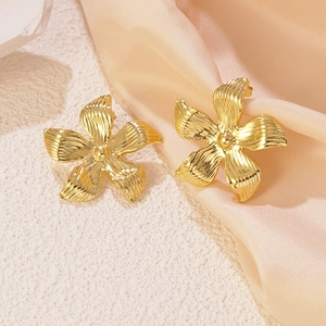 Elegant gold flower pearl earrings with textured petals on a pink silk background