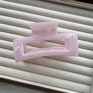 Close-up of pink marble pattern square hair claw clip on soft beige velvet display tray