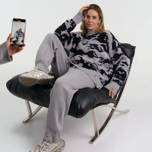 Detailansicht von grauem und schwarzem Strickpullover mit passender Hose am Modell