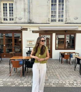 Outdoor street style view of grass green knit vest and white wide-leg tie-waist pants