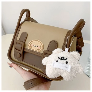 Detail of retro color-block shoulder bag with puppy embroidery and plush charm accessory