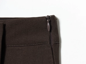 Dettaglio macro di pantaloncini in twill marrone scuro con cerniera invisibile piatta