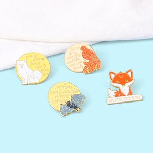 Détail de broches en émail colorées avec des citations motivantes sur tissu bleu