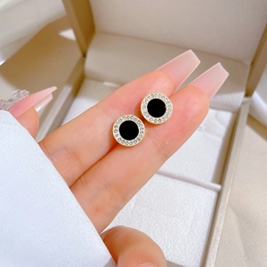 Detailed view of round black agate earrings with gold trim and zircon crystals