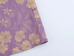Detail of purple jacquard fabric featuring gold floral patterns and fine stitching work