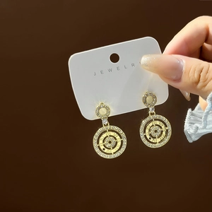 Sparkling gold clock-inspired earrings with crystals and Roman numerals on white card
