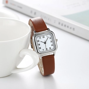 Détail d'une montre carrée argentée avec cadran blanc et bracelet en cuir marron