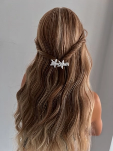 Détail de barrettes étoiles de mer argentées avec strass sur cheveux blonds bouclés