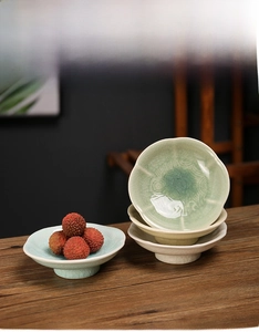 Detail of high-foot ceramic plates with ice-crack glaze in pale blue and beige tones
