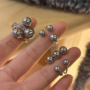 Detailed view of multiple silver polished stainless steel spherical bead rings on fingers