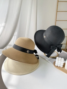 Detailed close-up of woven straw sun hats with black ribbons and chic bow accents