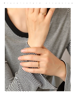 Detailed macro view of gold plated micro-inlaid zirconium chain and woven rings on finger