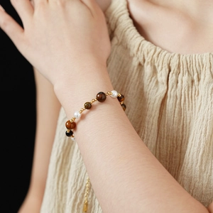 Detail of beaded bracelet with tiger eye stones, pearls and gold-plated hollow charms