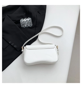 Detail view of white matte leather crossbody bag with unique wavy curved bottom design