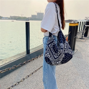 Outdoor lifestyle shot of a large blue paisley canvas tote bag on a model shoulder