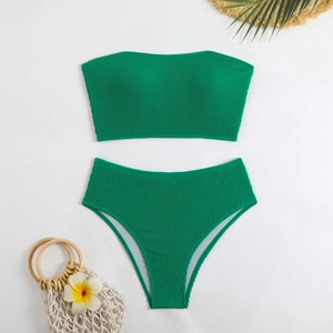 Close-up of green smocked fabric texture on bandeau bikini set with beach accessories