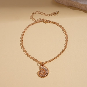 Detailed close-up of a golden seashell pendant necklace on a natural stone background