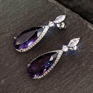 Vue macro de boucles d'oreilles en goutte d'argent avec pierres violettes et zircons brillants