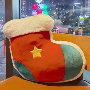 Macro view of Christmas stocking plush pillow with star embroidery on leather chair