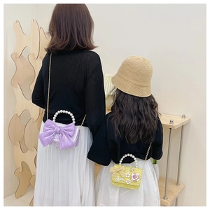 Détail de mini sacs en tweed avec poignées en perles et nœuds sur parent et enfant