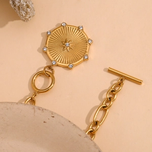 Close-up of an 18K gold-plated starburst medallion necklace with OT toggle clasp detail