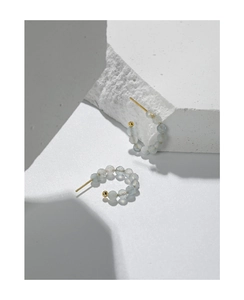 Dettaglio di orecchini a cerchio a C in argento S925 con perle sfaccettate in acquamarina
