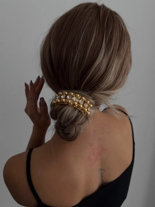 Detail of gold metal hair clip with sparkling crystals worn on a low hair bun
