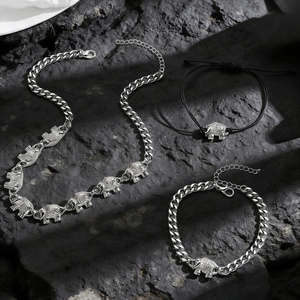 Vintage silver elephant necklace and bracelet set displayed on a dark stone background