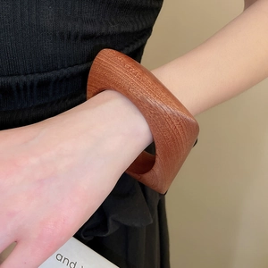 Détail macro du bracelet géométrique en bois montrant le grain fin et le fini acajou