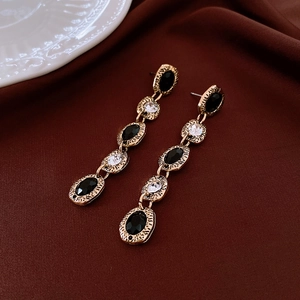 Baroque style drop earrings with black and white gems on luxury silk fabric background